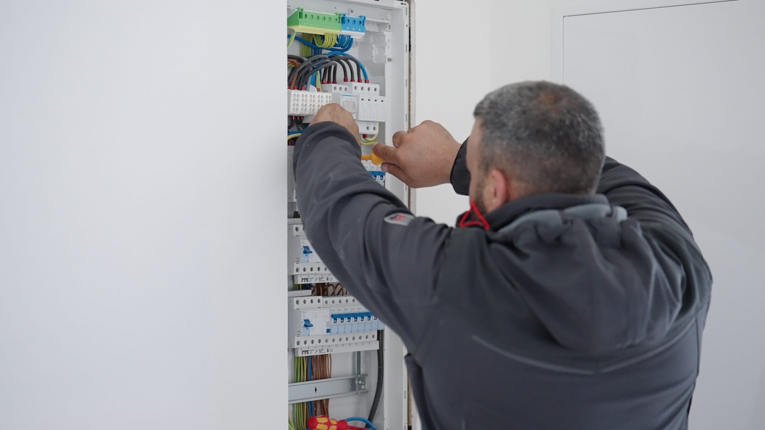 Electrician mounting a distribution board in a new build