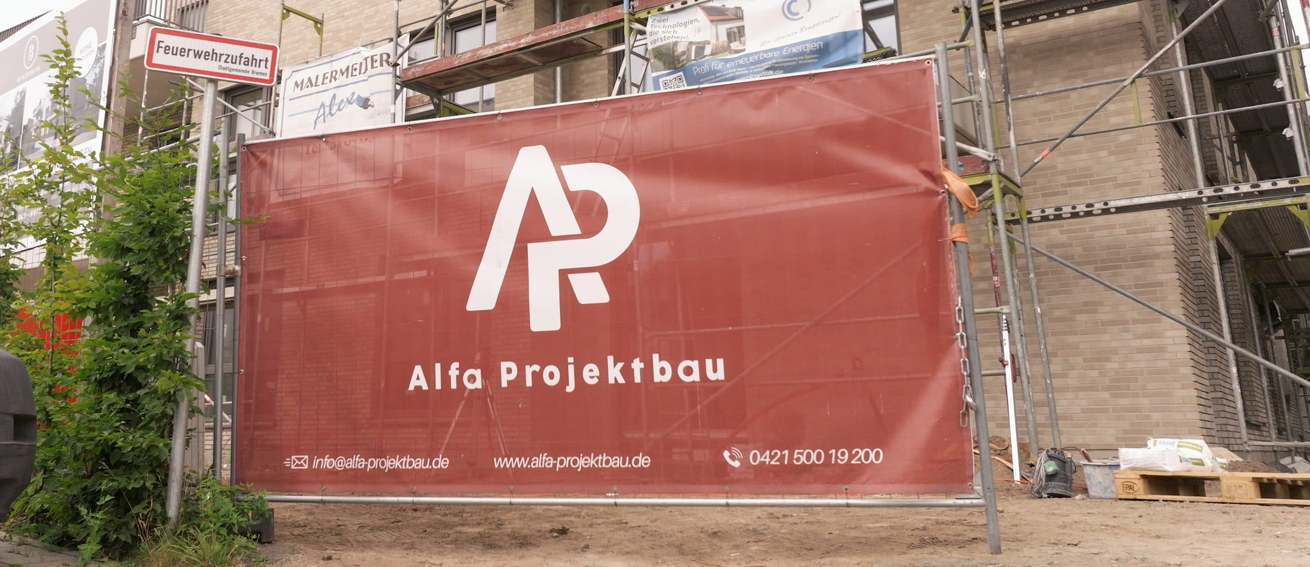 Bauzaun-Banner der Alfa Projektbau GmbH vor einer eingerüsteten Baustelle in Bremen